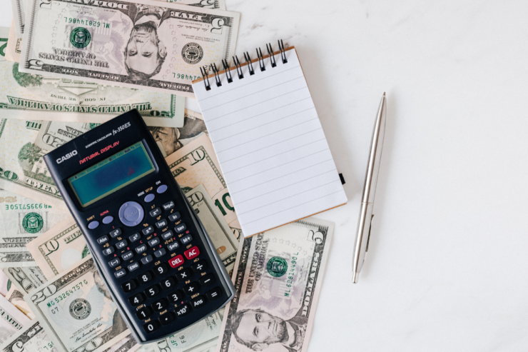 Calculadora, billetes de dólar y libreta en blanco — errores de inversión y estafa en cajeros ATM