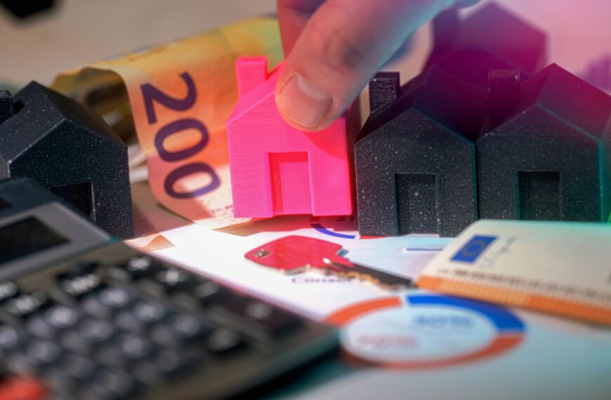 Miniature houses, Euro bills, and calculator representing real estate investment.